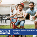 Little boy learning how to ride a bike with his family. Featured image for Summer Safety Tips for Kids and Families blog